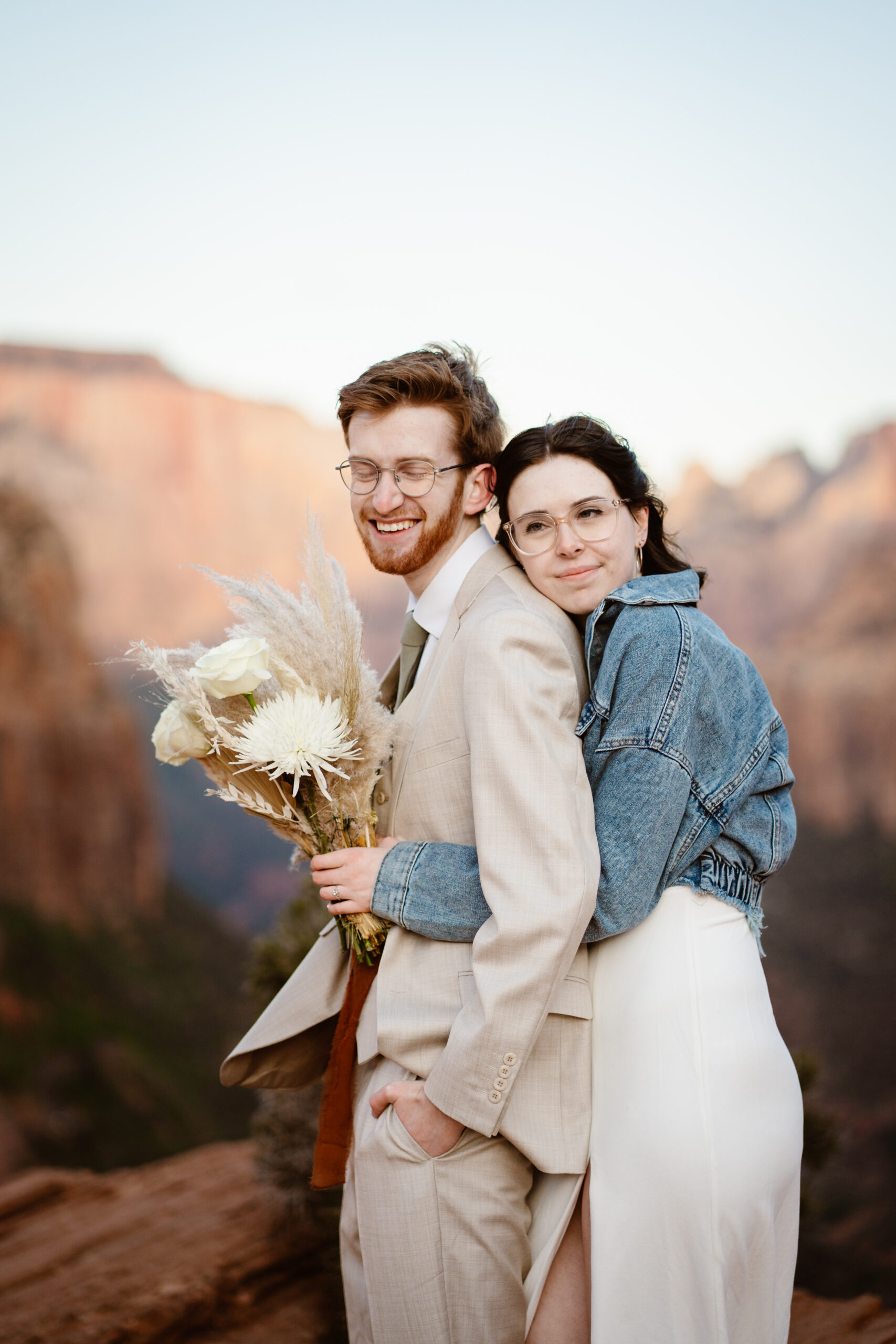 A couple shares an embrace in front of overlook background during their elopement.